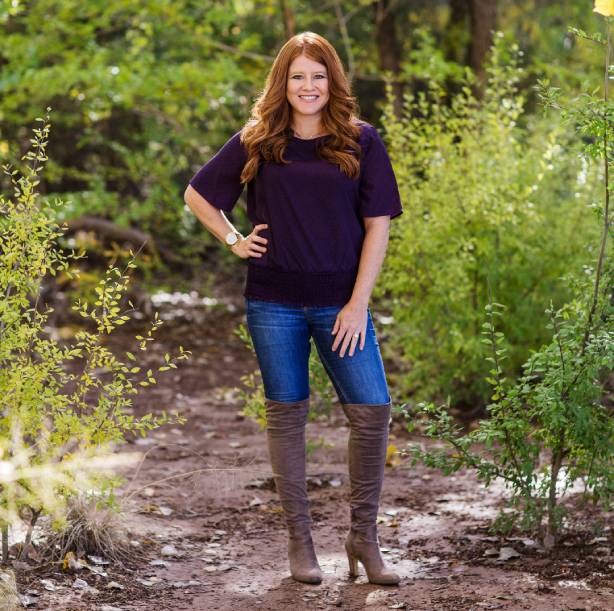 A woman standing in the woods wearing boots.