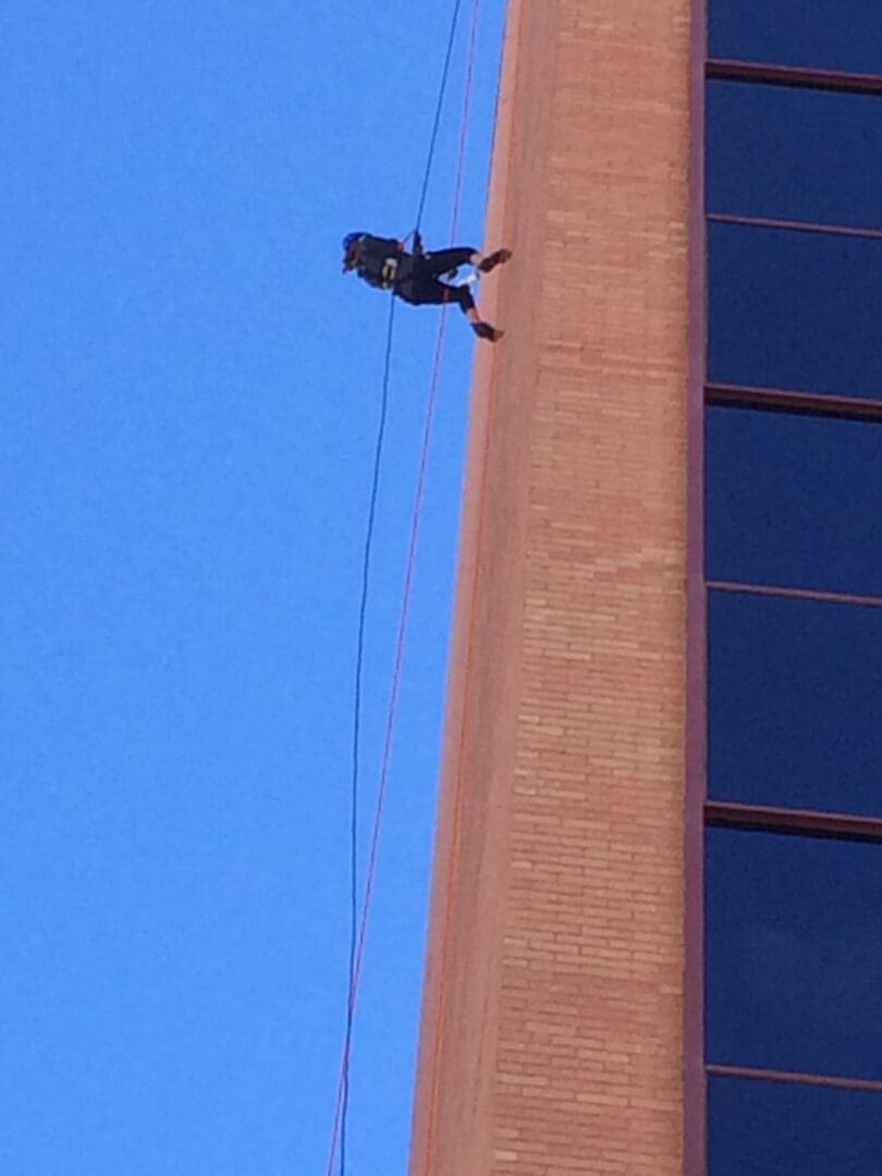 A man climbing a building by a rope